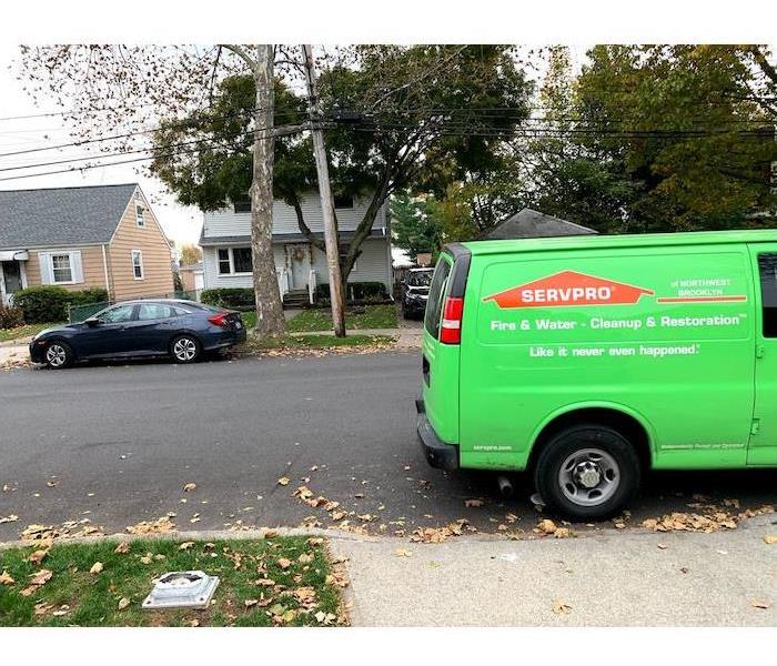 Green service van parked in front of a home on a residential street
