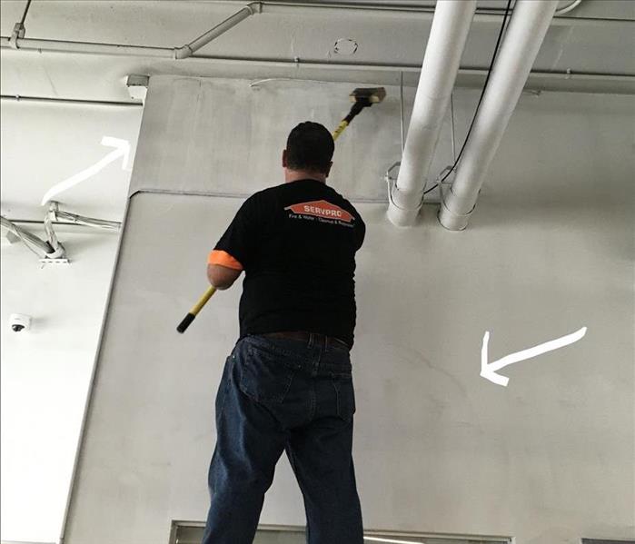 A SERVPRO crew member dry cleaning a soot-damaged wall