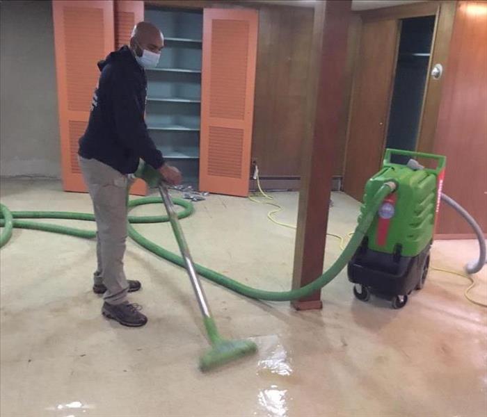 tech, vacuuming flooded floor in basement