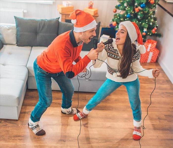 A couple doing holiday karaoke in their living room.